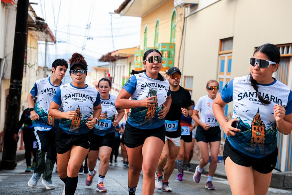 Participants in a vibrant street race wearing athletic wear and numbered bibs, running energetically.
